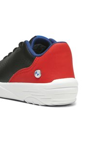 Schwarze Ledersneaker mit roten und blauen Akzenten, strukturiertem Hinterteil, weißer Sohle und kreisförmigem Logodetail. Runde Form mit glatter Oberfläche.