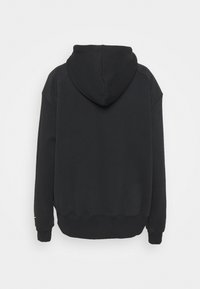 Svart hoodie i mjukt tyg. Har raglanärmar och ribbade muddarna. Slät textur, minimalistisk design, inga synliga logotyper.