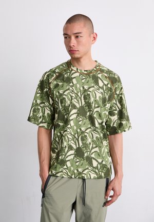 Short-sleeve shirt in green and cream with a botanical pattern, made of lightweight fabric; features raglan sleeves and contrasting seams.