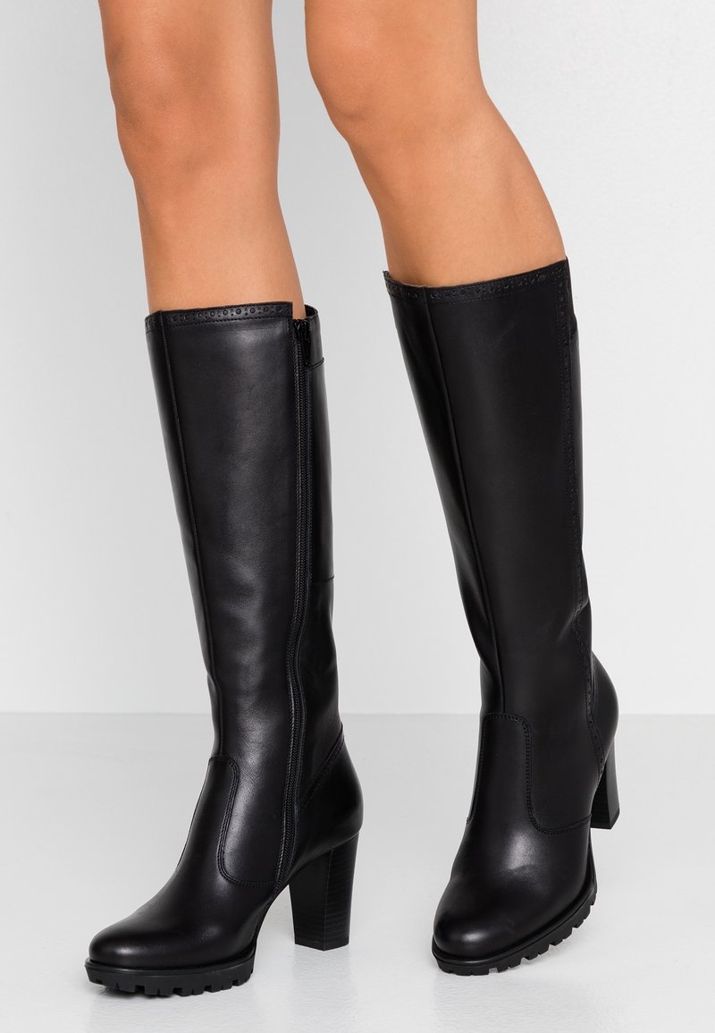 Botas negras de cuero hasta la rodilla con tacón grueso, diseño elegante, cierre lateral con cremallera y suela de goma texturizada para mejor agarre.