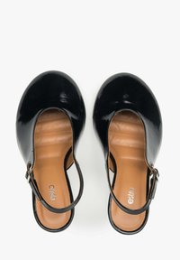 Zwarte lakleren slingback schoenen met een ronde neus, blootgestelde zijkant, gestikte binnenzool en verstelbare enkelsluiting.