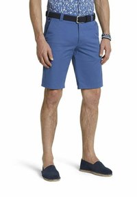 Shorts en coton bleu avec une coupe slim, des poches latérales et une ceinture en tissu noir tissée au niveau de la taille. Portés avec des espadrilles bleu marine.