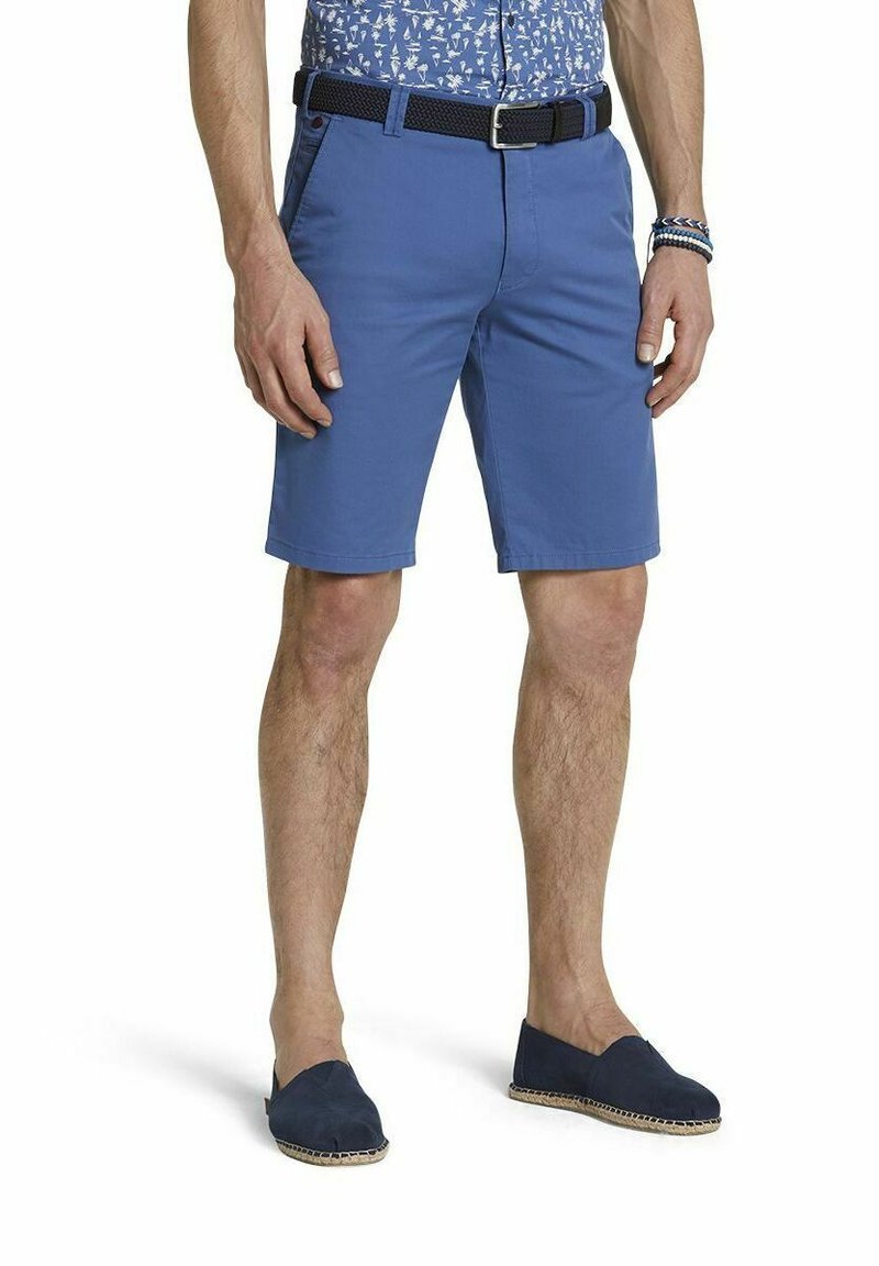 Shorts en coton bleu avec une coupe slim, des poches latérales et une ceinture en tissu noir tissée au niveau de la taille. Portés avec des espadrilles bleu marine.