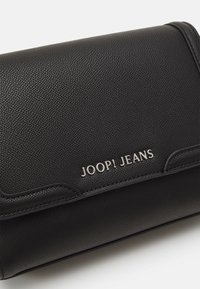 Borsa a tracolla in pelle nera con texture, con logo argentato "JOOP! JEANS", dotata di una patta liscia e dettagli di cucitura discreti.