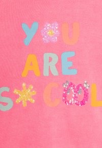 Tessuto rosa con testo multicolore che dice "SEI FANTASTICO", con accenti di paillettes sulle grafiche di fiori e sole, creando un design giocoso.