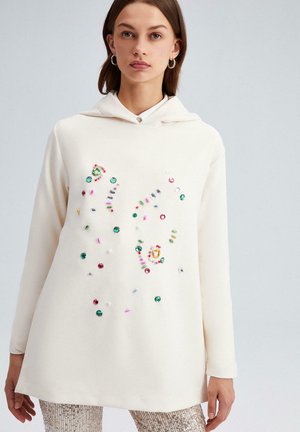 Crème hoodie met kleurrijke versieringen, inclusief pailletjes en kralen in diverse vormen, textuurstof en lange mouwen.