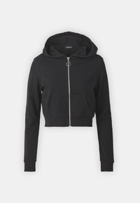Sudadera corta negra hecha de una tela suave. Cuenta con un cierre frontal con cremallera, una gran capucha y un bolsillo delantero. Mangas largas con puños de canalé.