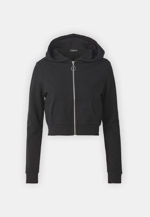 Svart cropped hettegenser laget av mykt stoff. Har glidelås foran, en stor hette og en lomme foran. Lange ermer med ribbestrikkede mansjetter.