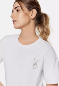 Witte katoenen T-shirt met een grafisch ontwerp op de borst van een hand die een vredesteken maakt, aangevuld met een bladdetail.
