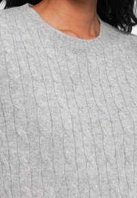 Maglione grigio a maglia con collo rotondo, caratterizzato da un motivo testurizzato e un tessuto morbido, che mette in risalto i dettagli dei punti intricati.