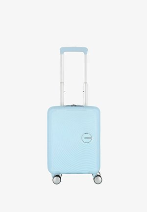 Valise cabine rigide bleue avec un design à rainures, équipée d'une poignée rétractable, de quatre roues et d'un accent logo argent.