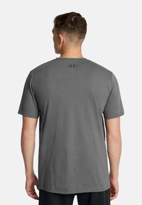 Grå kortærmet t-shirt lavet af blødt stof, med rund halsudskæring og et lille sort logo på ryggen nær kraven.