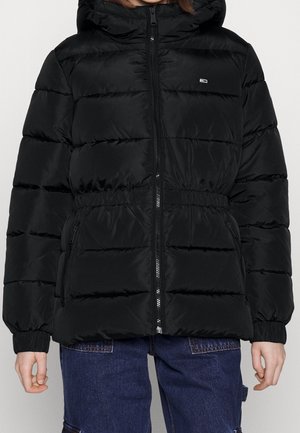 Sort dunjakke med hætte, elastisk talje og lynlås foran, båret over blå denim bukser.