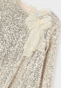 Abito in beige con strass luminosi che coprono la superficie. Presenta un colletto arricciato beige e un delicato fiocco di nastro trasparente.