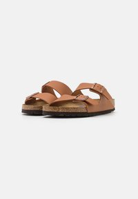 Brown leather sandals with two adjustable straps and buckles, cork footbed, textured black outsole, and a minimalist design.