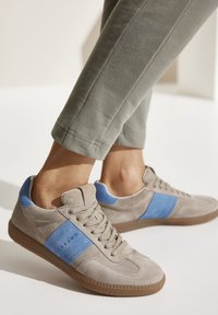 Wildledersneaker in Hellgrau mit blauer Akzentlinie. Low-Top-Design, runde Zehenform und Gummisohle mit strukturiertem Grip.