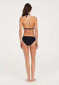 Čierny bikinový set s halter topom so šnúrkou na krku a zodpovedajúcimi vysokými nohavičkami; rebrovaná textura a minimálne detaily značky.
