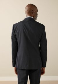 Dunkelgrauer Herrenanzug mit glatter Textur, schmaler Passform und einem einfachen Schlitz hinten. Verfügt über Knöpfe am Ärmelaufschlag und einen Notch-Revers.