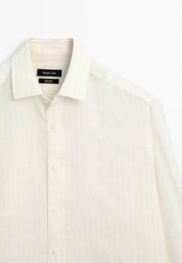 Weißes Leinenhemd mit langen Ärmeln, Kragen und Knöpfen, mit sichtbarem Markenetikett Massimo Dutti im Nackenbereich.