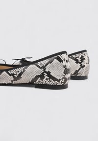 Ballerines avec un motif serpent noir et blanc, finition lisse et bout rond, dotées d'une bordure noire et d'une semelle flexible.