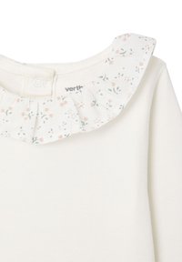 White top with a floral-patterned ruffle collar featuring pink and green accents. Includes a snap button closure at the back neckline.