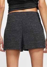 Svarta, texturerade shorts med avslappnad passform, med ett elastiskt midjeband och rullad fåll, tillverkade av ett mjukt, andningsbart material.