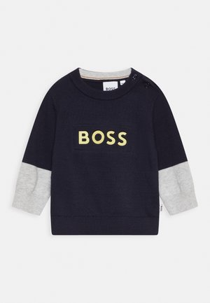 Granatowy sweter dla malucha z szarymi mankietami, okrągłym dekoltem, zapinany na guzik przy ramieniu i żółtym napisem "BOSS" z przodu.