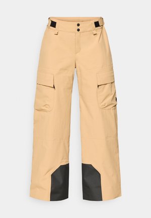 Pantalons cargo beiges avec plusieurs poches latérales, un ourlet inférieur noir et une fermeture à crochets et boucles à la taille, avec un double bouton de fixation.