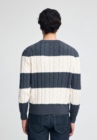 Sweter w paski z plecionki z naprzemiennymi granatowymi i kremowymi poziomymi paskami, z prążkowanymi mankietami i dekoltem oraz teksturowanym wykończeniem.