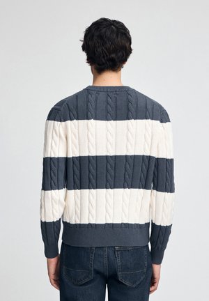 Maglione a maglia a righe, caratterizzato da strisce orizzontali alternate in navy e crema, con polsini e scollatura a coste e una finitura testurizzata.