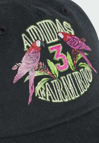 Czarny czapka baseballowa z haftowanymi różowymi papużkami, zielonymi liśćmi oraz napisem "ADIDAS 3 FARM RIO". Napis ma teksturowane, błyszczące wykończenie.