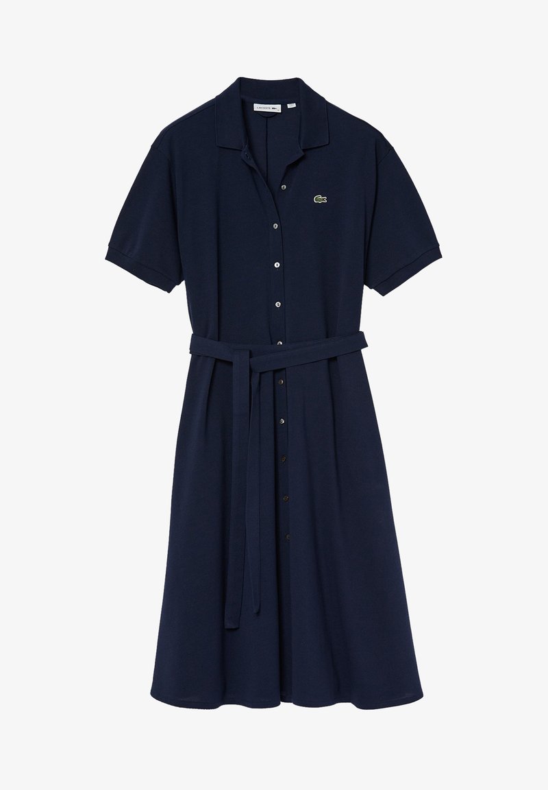 Marinblå klänning i mjukt tyg, med krage, korta ärmar, knapplås och midjeband för en figurnära look. Har en liten logotyp.