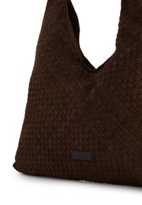 Brun vævet ruskinds taske med en blød form, der har en tekstureret overflade og et lille prægembossed logo mærke nederst.
