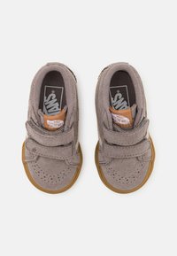 Zapatos infantiles de ante gris con suela de goma marrón, que cuentan con dobles correas de Velcro y un logo en la lengüeta. Punta redondeada y detalles cosidos.