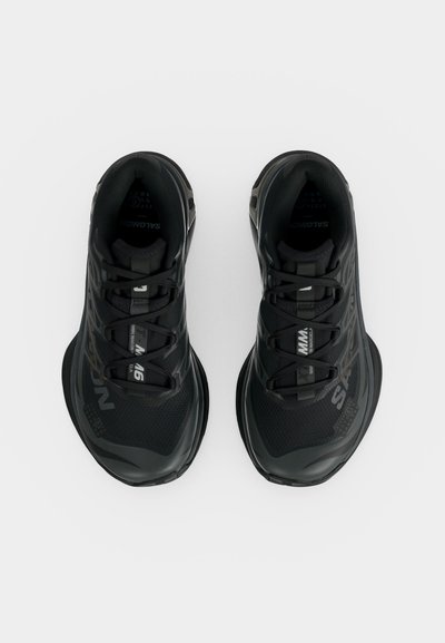 Ζευγάρι μαύρα αθλητικά παπούτσια Salomon με κλείσιμο με κορδόνια, ορατό λογότυπο και ανθεκτική σόλα, από πάνω σε λευκό φόντο.