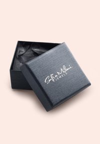 Svart texturerad smyckeslåda med ett passande lock, med en silverlogotyp "Sofia Milani Jewels" på framsidan. Inuti är den klädd med mörkt silkespapper.
