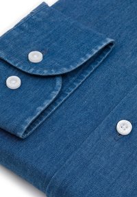 Kołnierz koszuli dżinsowej z dwoma białymi guzikami, niebieska tkanina z delikatną teksturą. Złożony na brzegach, eksponujący detale ściegów.