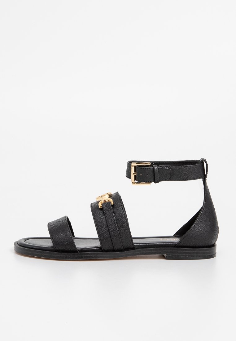 Sandal in pelle nera con due larghe cinghie, una cinghia alla caviglia con fibbia e un accento dorato. Suola piatta con finitura texture.