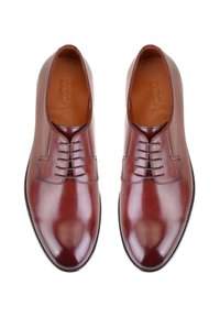 Chaussures en cuir marron foncé avec une finition brillante, comportant cinq œillets, des coutures détaillées et un design de bout rond lisse.
