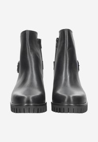 Black leather ankle boots with a smooth texture, zip closure, and horizontal ribbing on the rubber sole. Features a minimalist design.