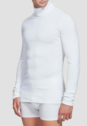 Maglione a maniche lunghe bianco con collo alto realizzato in materiale morbido, design aderente, texture liscia, abbinato a pantaloni boxer bianchi.