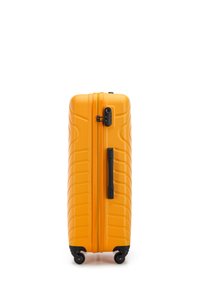 Valise rigide de couleur orange vif avec une surface texturée et des éléments en métal noir, dotée d'une poignée latérale et de quatre roues pour la mobilité.