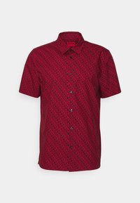 Camisa de manga corta y botones en tejido rojo brillante con un patrón de espirales negras, que presenta un collar y cinco botones negros en el frente.