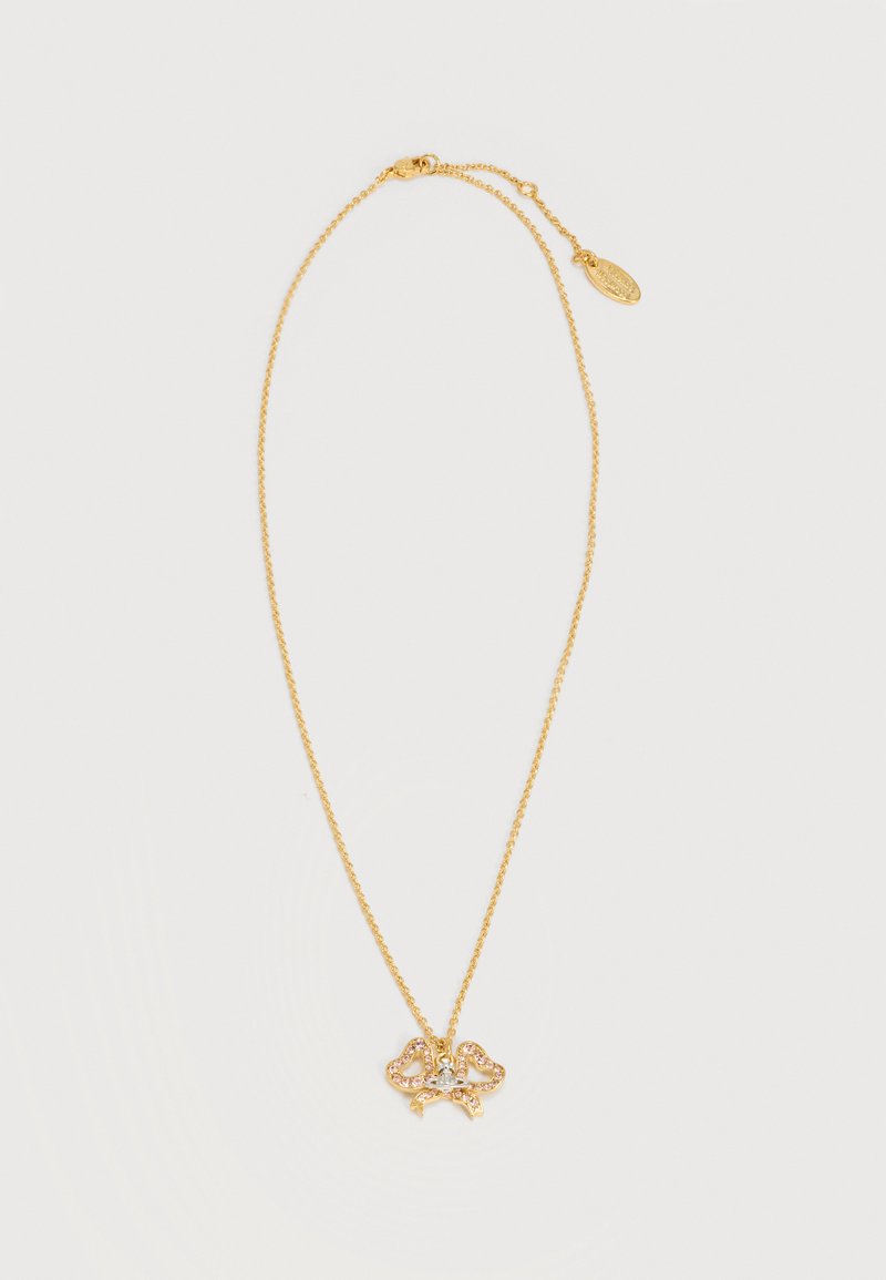 Trapiantės auksinės grandinėlės vėrinys su širdies formos brangakmenio pakabuku ir mažu dekoratyviniu kaspinu ant balto fono.