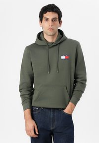 Felpa verde oliva con tasca a marsupio frontale, cappuccio regolabile con cordino e un logo con strisce rosse, bianche e blu sul petto.
