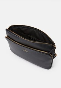 Schwarze Ledertasche mit zwei Reißverschlussfächern, goldfarbenen Beschlägen, schlanker Form und glatter Textur. Das Innenfutter verfügt über ein Etikett.