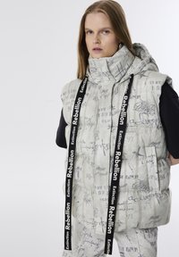 Lichtgrijze puffer vest met capuchon, voorzien van abstracte zwarte handschriftpatronen en twee zwarte banden met het label "Extinction Rebellion."
