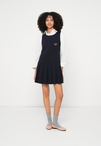 Ναυτικό πλισέ φόρεμα με εφαρμοστό μπούστο και λευκό πουκάμισο μακρυμάνικο από μέσα. Διαθέτει τσέπη στο στήθος με κέντημα "tommy girl".