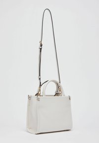 Sac à main en cuir blanc avec une forme structurée, des poignées supérieures et une bandoulière détachable et réglable. Doté de ferrures dorées et d'accents noirs contrastants.