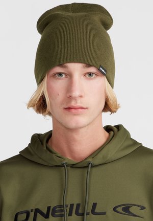 Olivengrøn ribbet strikhue med ombukket skygge og et lille sort logo-mærke. Stoffet ser blødt ud med en let struktur.
